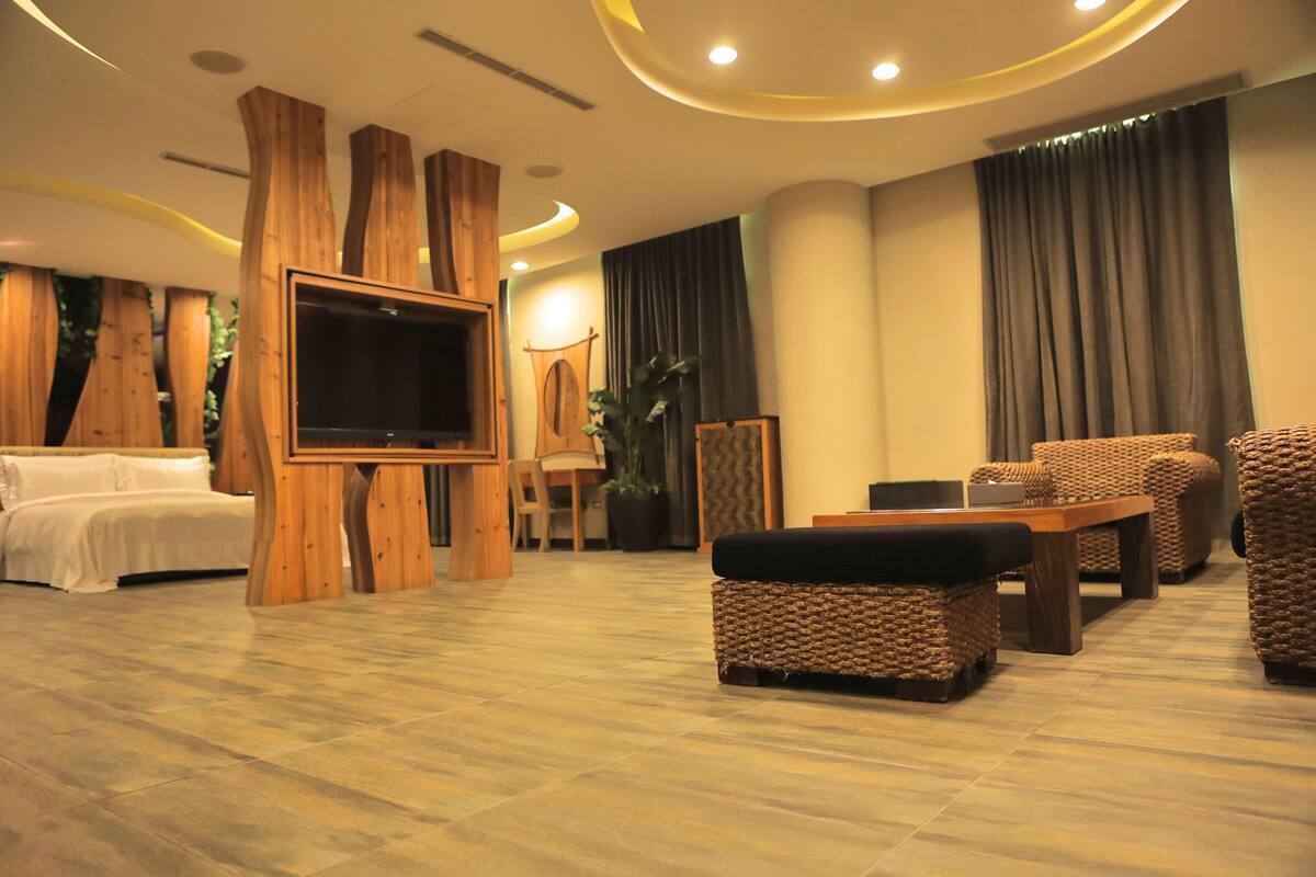 A modern living room with a flat-screen TV, wooden furniture, a sofa, and a dining table.