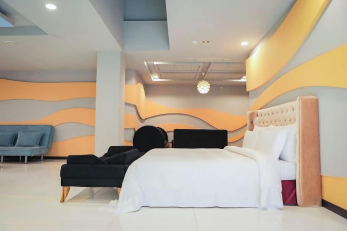 Une chambre à coucher moderne avec un lit, un canapé et un lustre.
