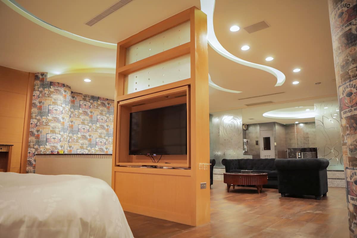A hotel room with a large bed, a TV, a sofa, and a coffee machine.