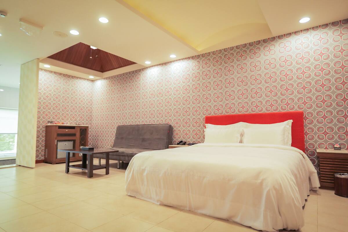 A hotel room with a bed, a desk, and a chair.
