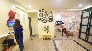 Eine Lobby mit Empfangsschalter, einer Wand mit Zahnrädern, einem Wandgemälde und einem Spielebereich.