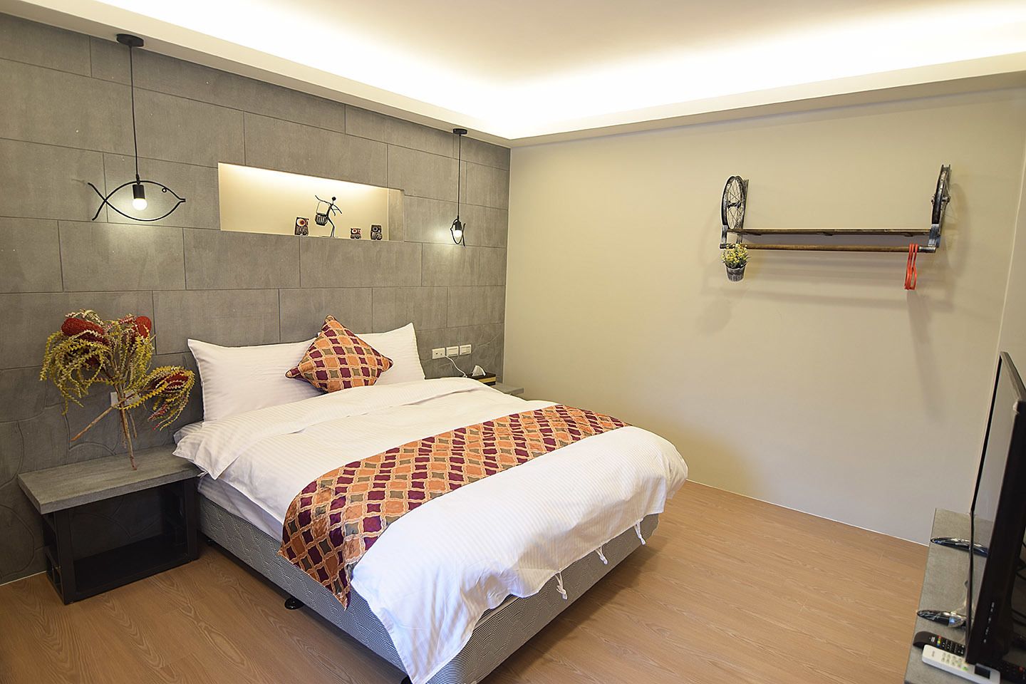 Een moderne hotelkamer met een groot bed, een nachtkastje, een wandplank en een vastgemaakte fiets.