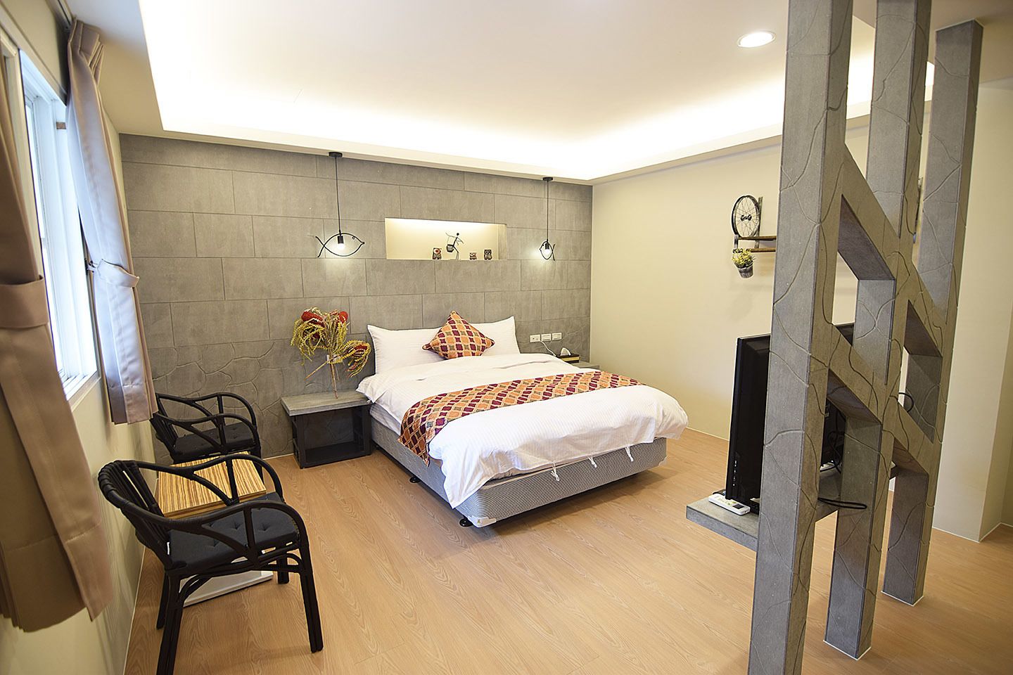 A modern bedroom with a bed, bedside tables, a TV, and a chair.