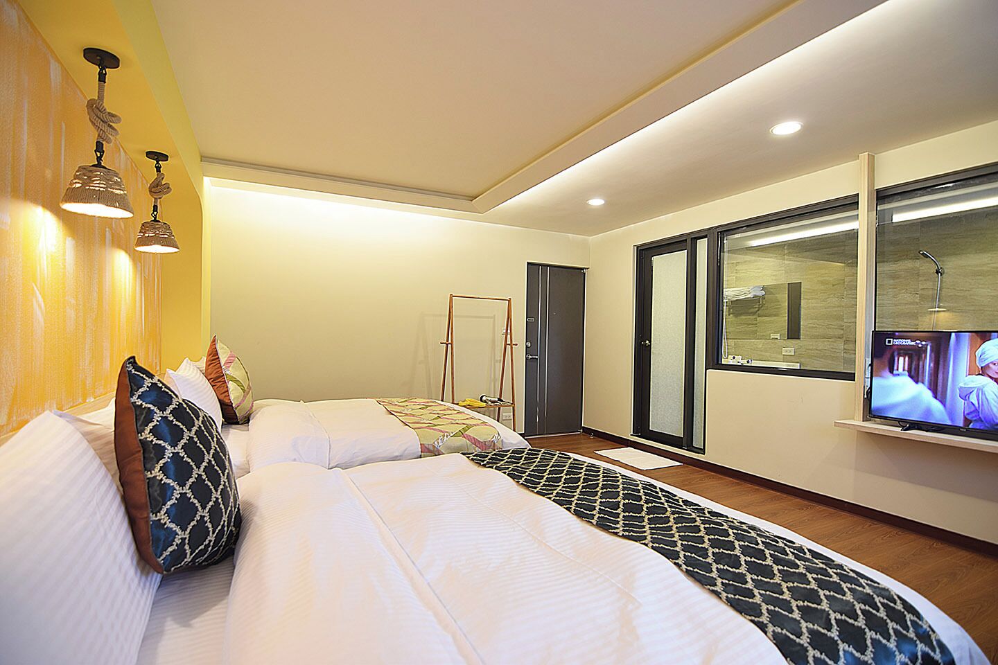 Habitación de hotel moderna con una cama grande, un televisor y una ventana con vistas.