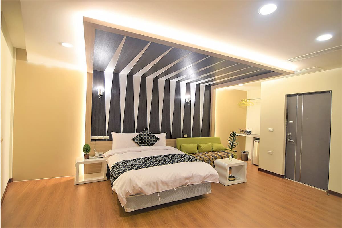 A modern bedroom with a large bed, bedside tables, a wardrobe, and a unique ceiling design.