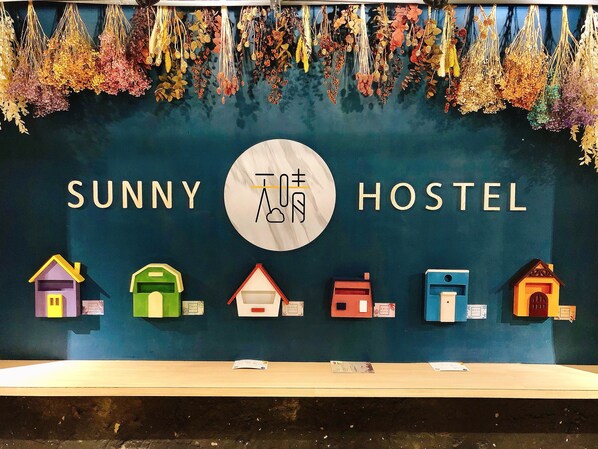 A sign for Sunny Hostel with a row of colorful house icons below it. - Taipei Sunny Hostel (Taipei)