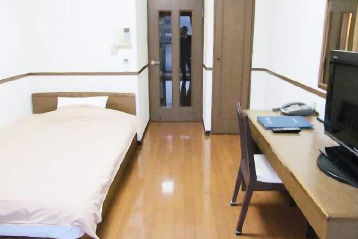 A hotel room with a bed, a desk with a computer, and a chair.