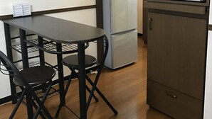 Una kitchenette compacta equipada con microondas, refrigerador y una pequeña mesa de comedor con sillas.