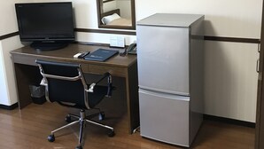 Un espacio de oficina pequeño con escritorio, computadora, silla, refrigerador y espejo.