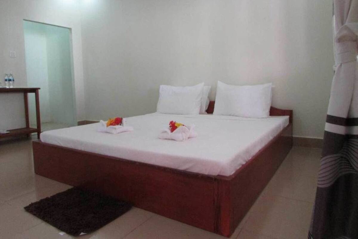 Una habitación de hotel con una cama individual, una mesita de noche pequeña y una alfombra oscura.