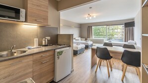 A modern kitchen with a microwave, sink, and refrigerator. There is a dining area with a table and chairs, and a bedroom with a bed and window. - Value Stay Residence Mechelen (Mechelen)