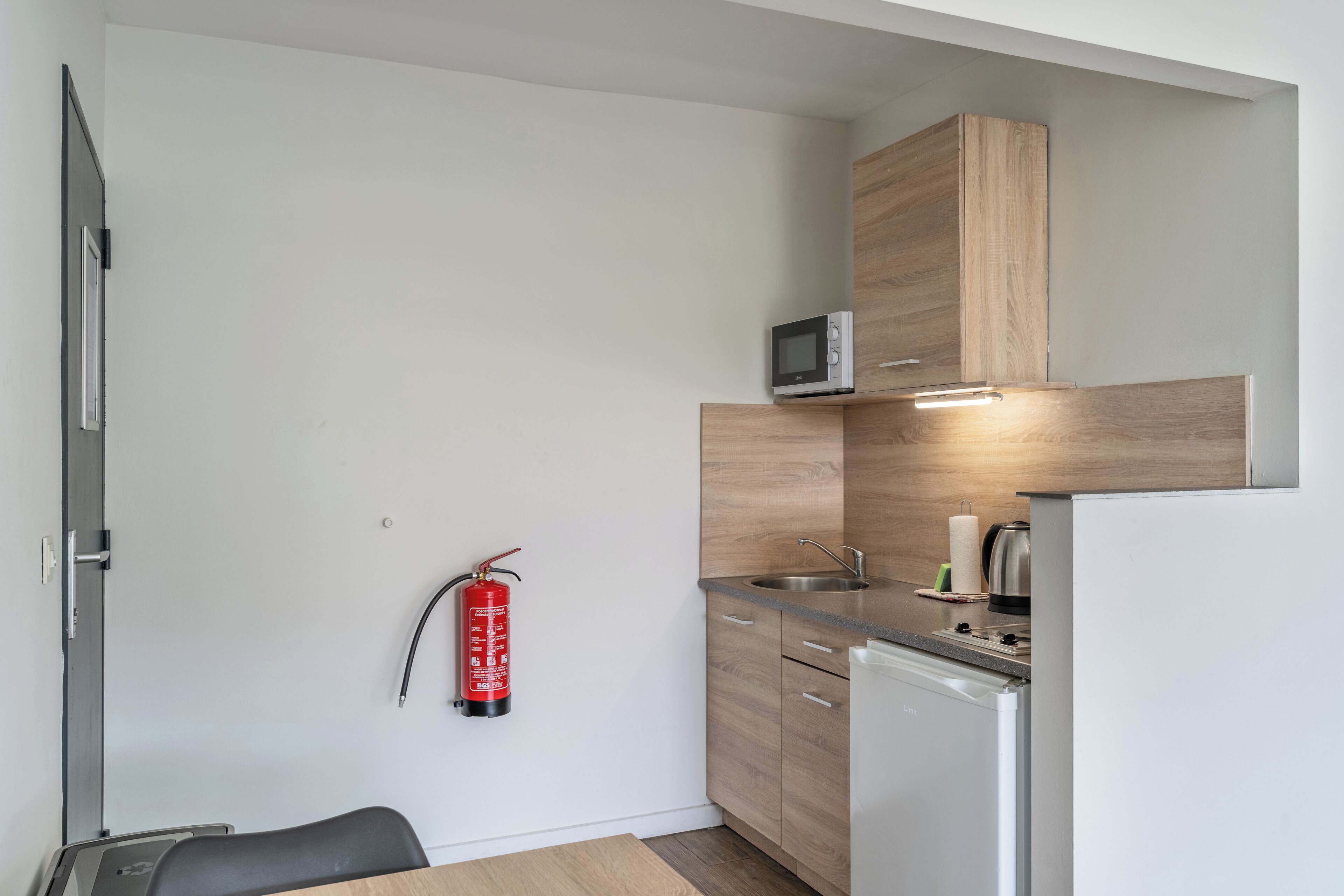 A compact kitchen with wooden cabinets, a microwave, a sink, and a dishwasher.
