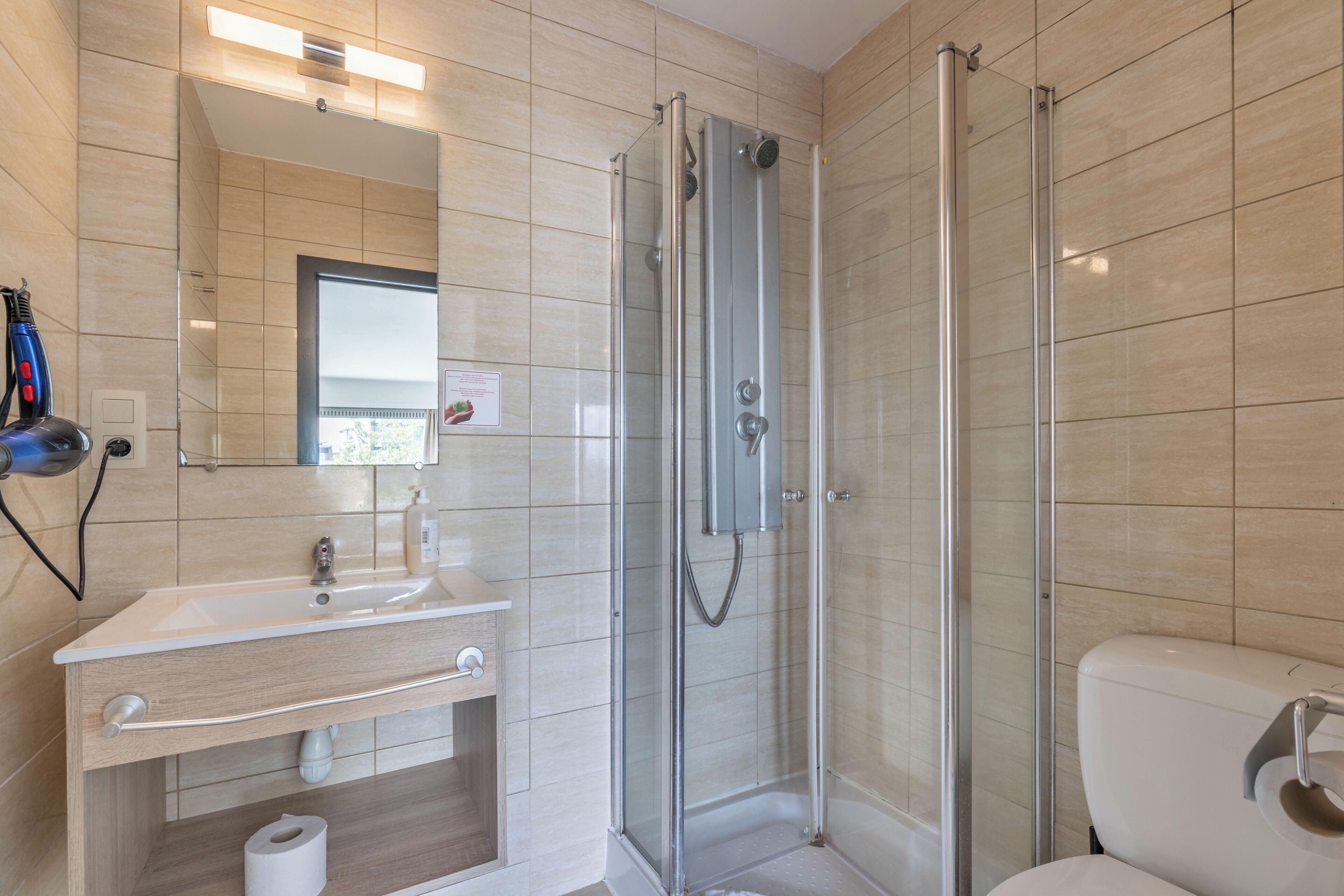 A modern bathroom with a glass-enclosed shower, a sink with a mirror, and a toilet.
