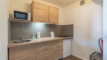 A compact kitchen with a microwave, sink, stove, and dishwasher.