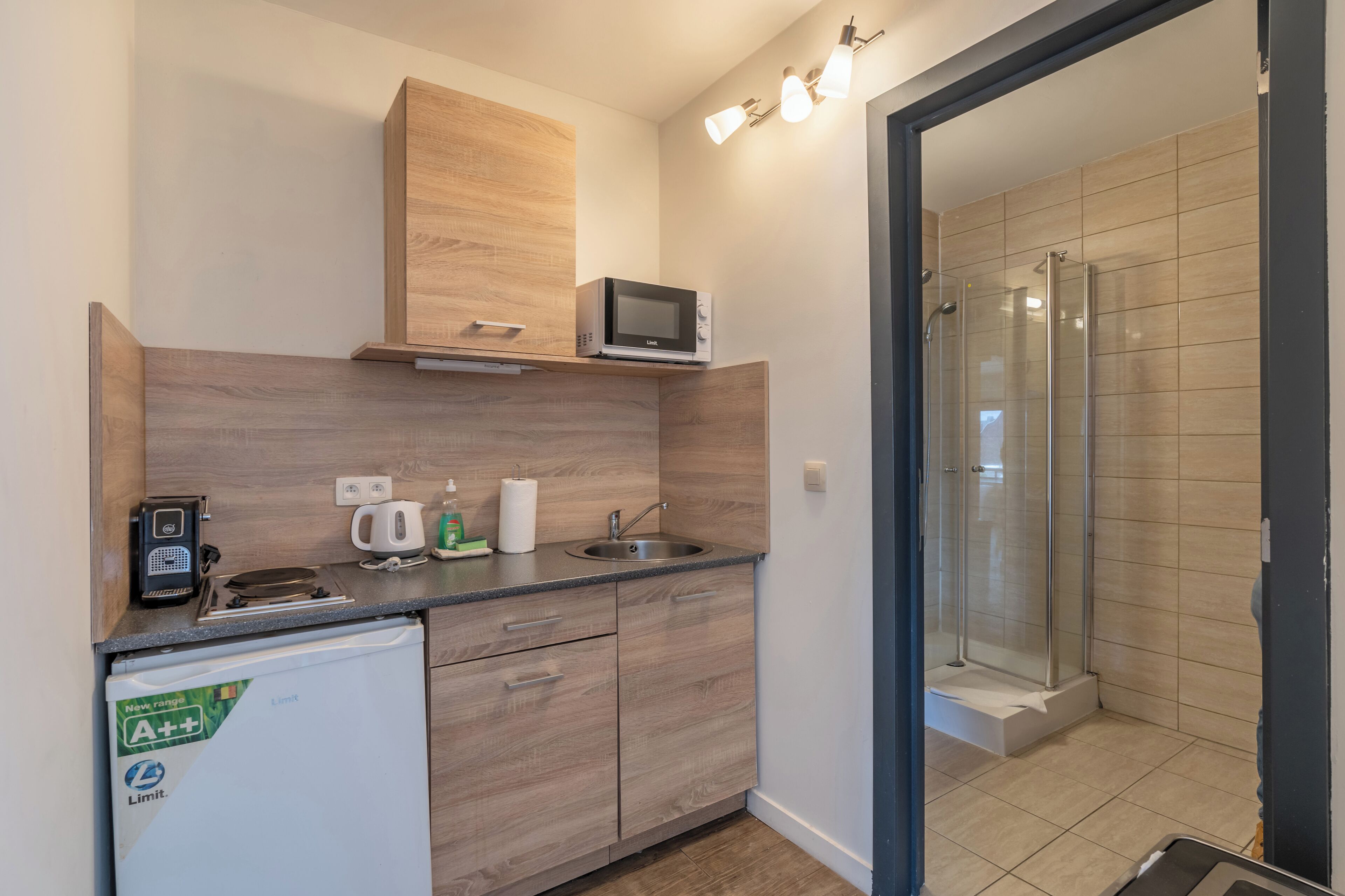 A compact kitchen with a microwave, coffee maker, and a small refrigerator.