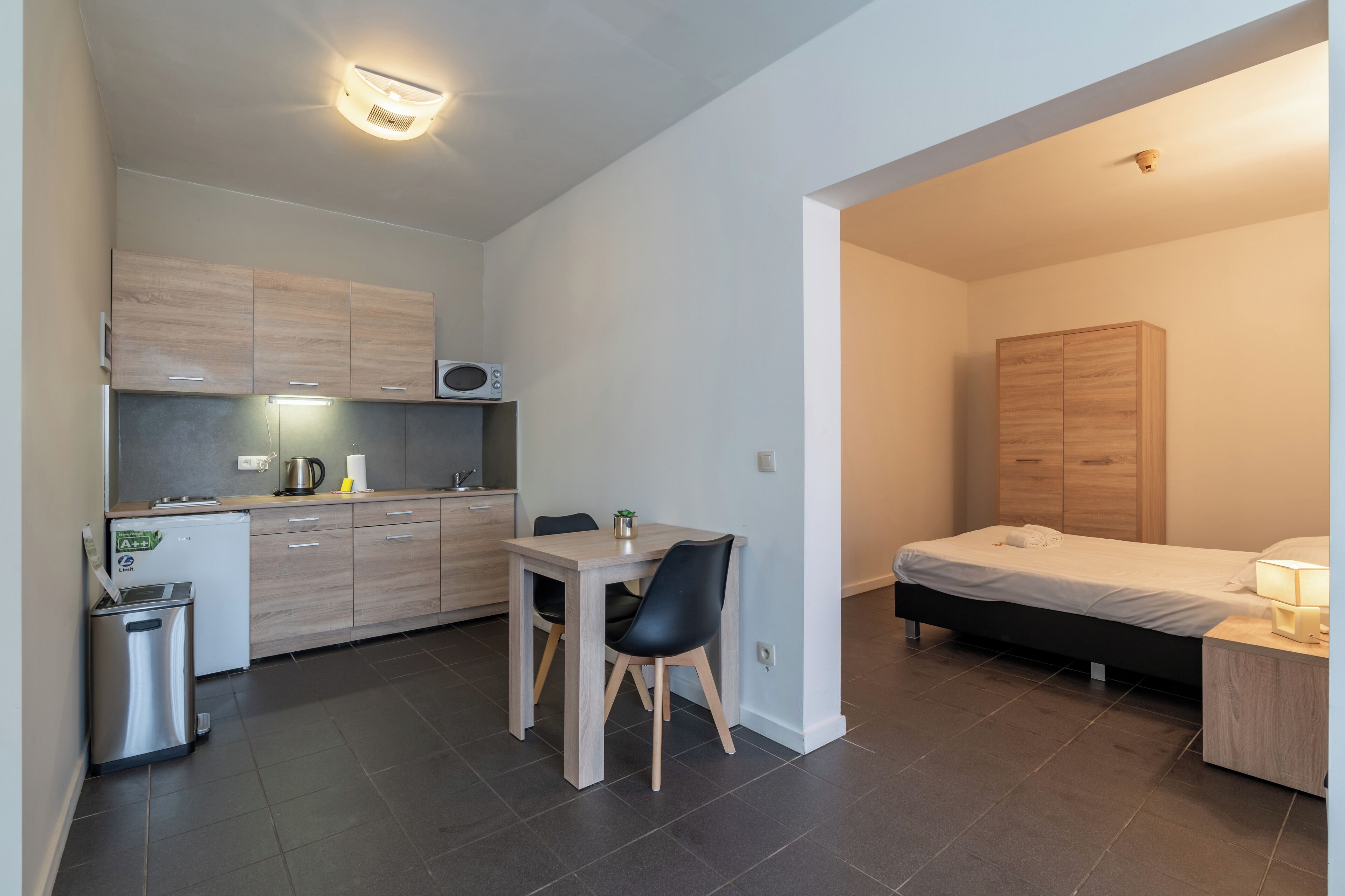 A compact living space with a kitchenette, a dining area, and a bedroom.