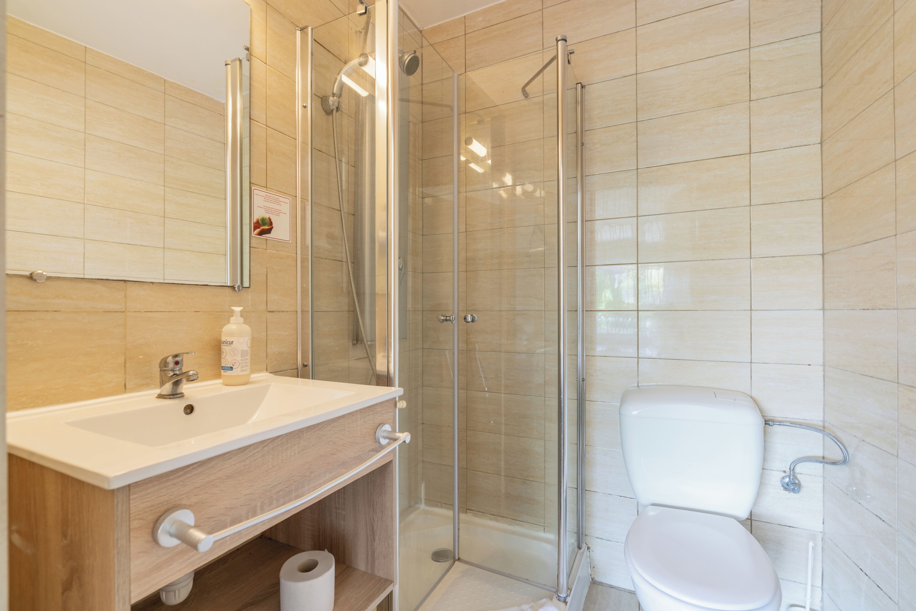 A modern bathroom with a glass-enclosed shower, a white sink, and a toilet.