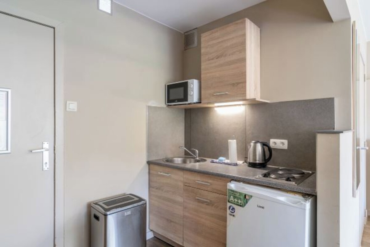 Una kitchenette compacta con microondas, pileta y pequeño refrigerador.