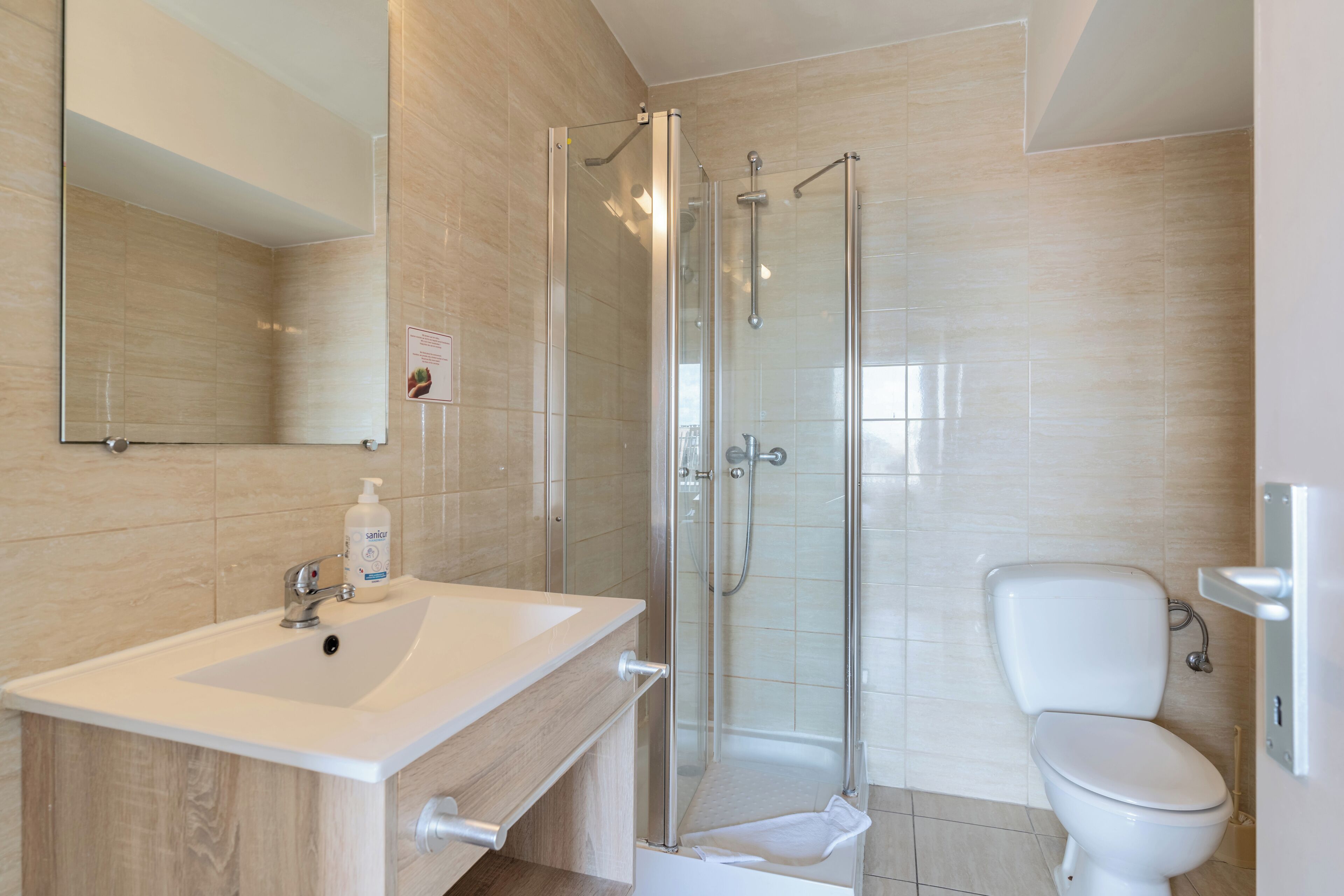 A modern bathroom with a glass-enclosed shower, a white sink, and a toilet.