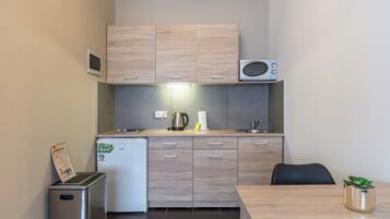 A compact kitchenette with a microwave, a small refrigerator, and a trash bin.