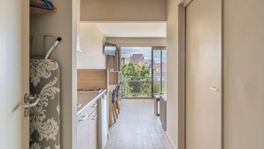 A narrow hallway leading to a balcony with a view of buildings and trees. - Value Stay Residence Mechelen (Mechelen)