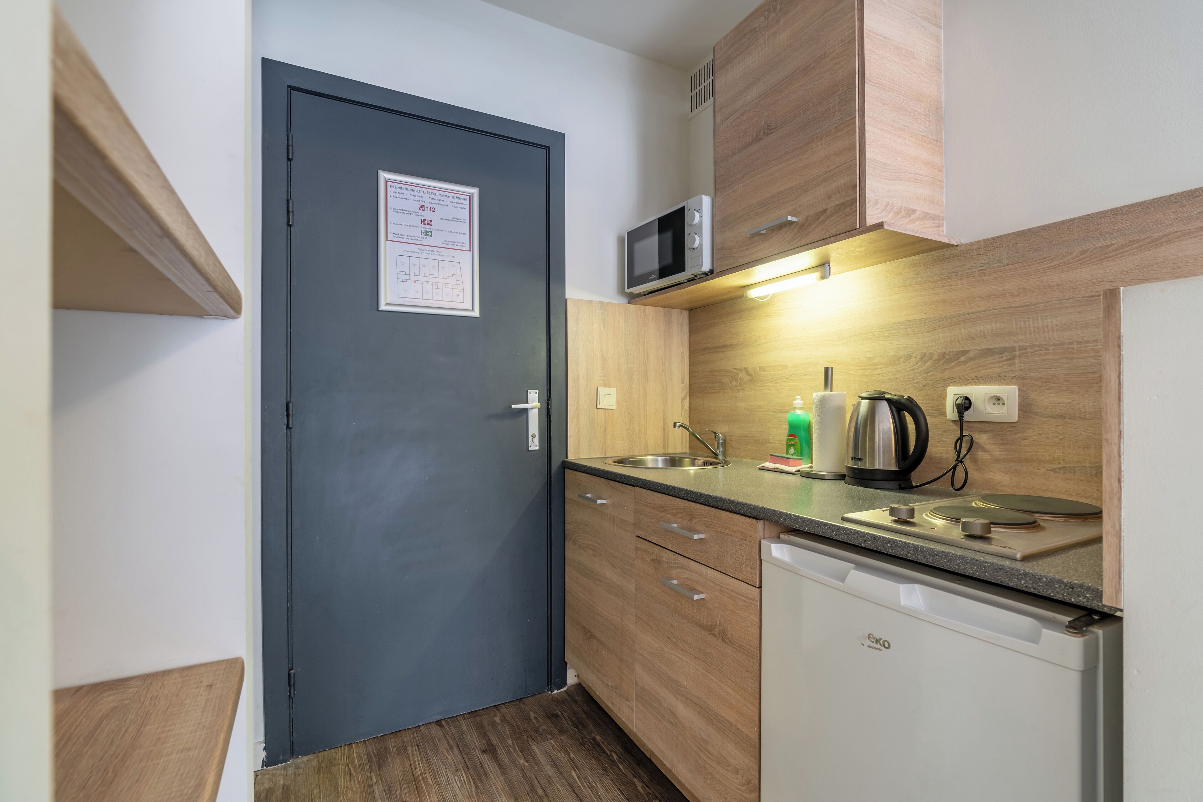 A compact kitchen with a microwave, kettle, and dishwasher.