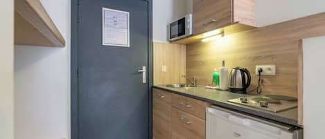 A compact kitchen with a microwave, kettle, and dishwasher.