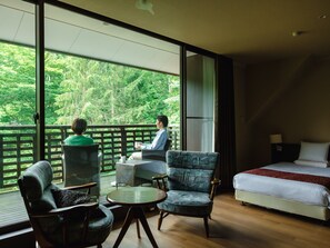 A room with a bed, a table, and two chairs. There is a balcony with a view of trees. - Wan Wan Paradise Takayama (Takayama)