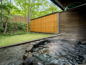 A hot spring area with a wooden fence, a stone pathway, and a wooden building. - Wan Wan Paradise Takayama (Takayama)
