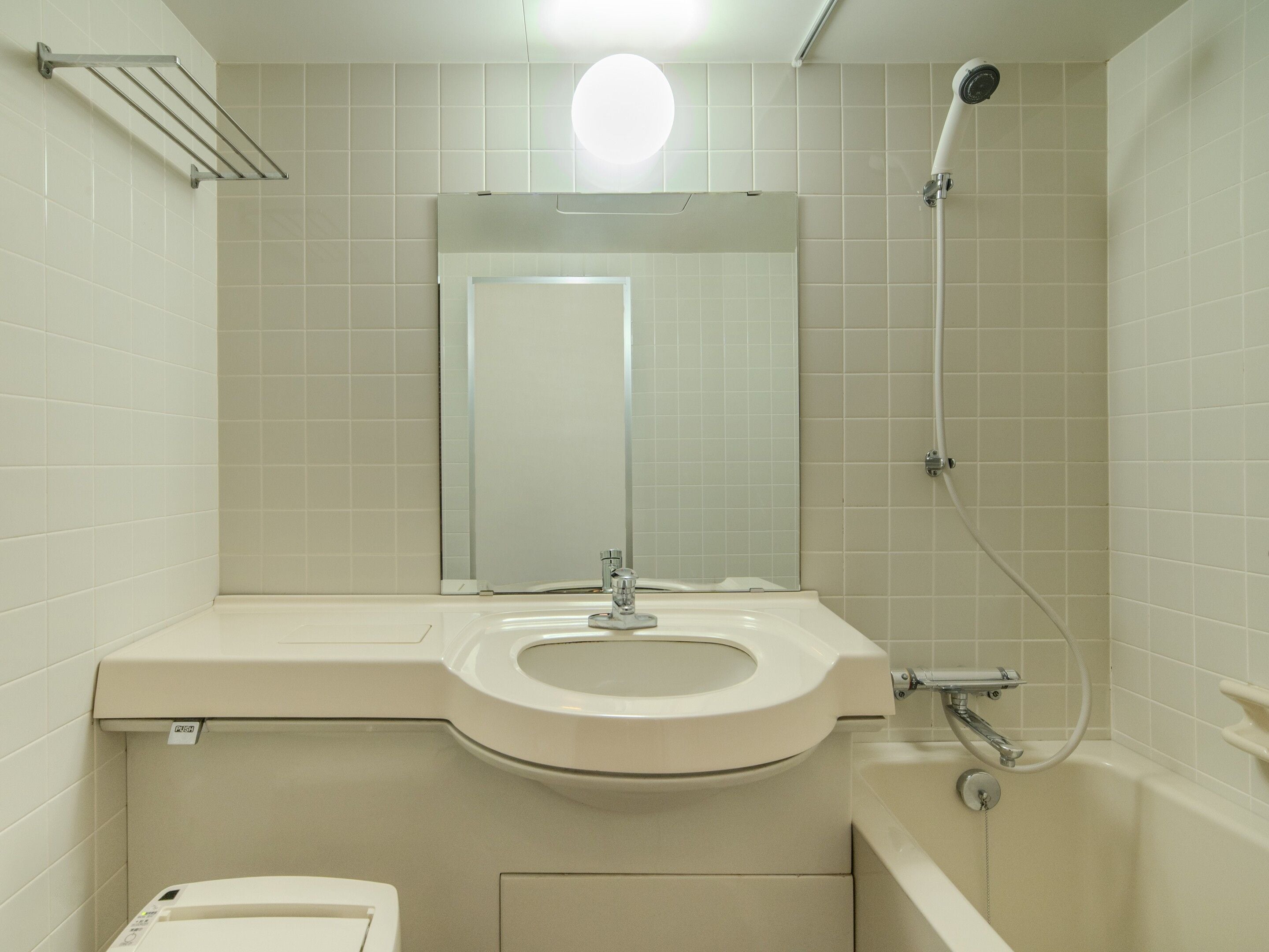 A bathroom with a toilet, sink, mirror, and shower.