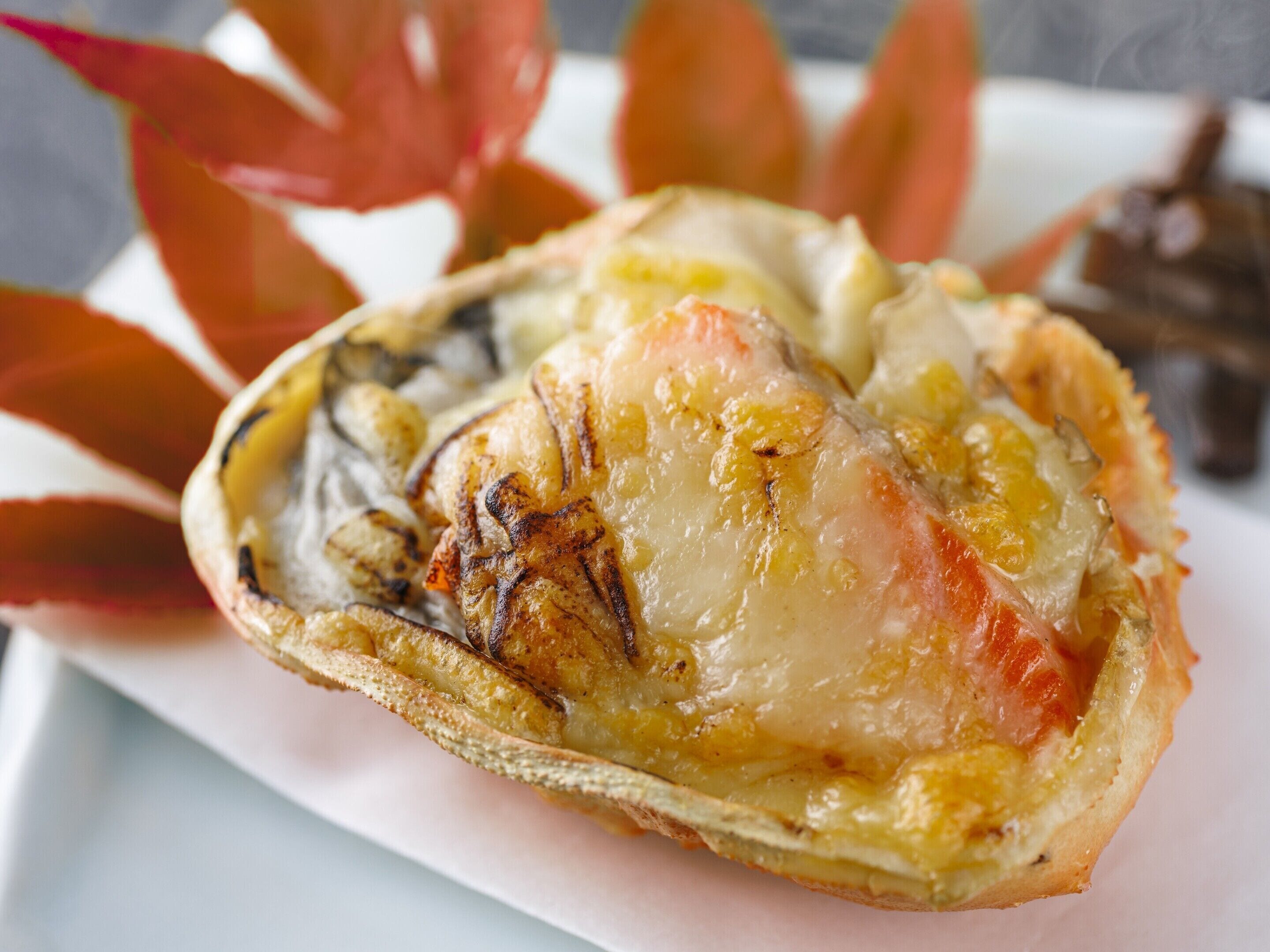 Primer plano de un plato de mariscos con salsa cremosa, posiblemente una cola de langosta, sobre un plato blanco.
