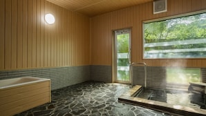 Un bain traditionnel de style japonais, avec un sol en pierre, des murs en bois et une grande fenêtre.