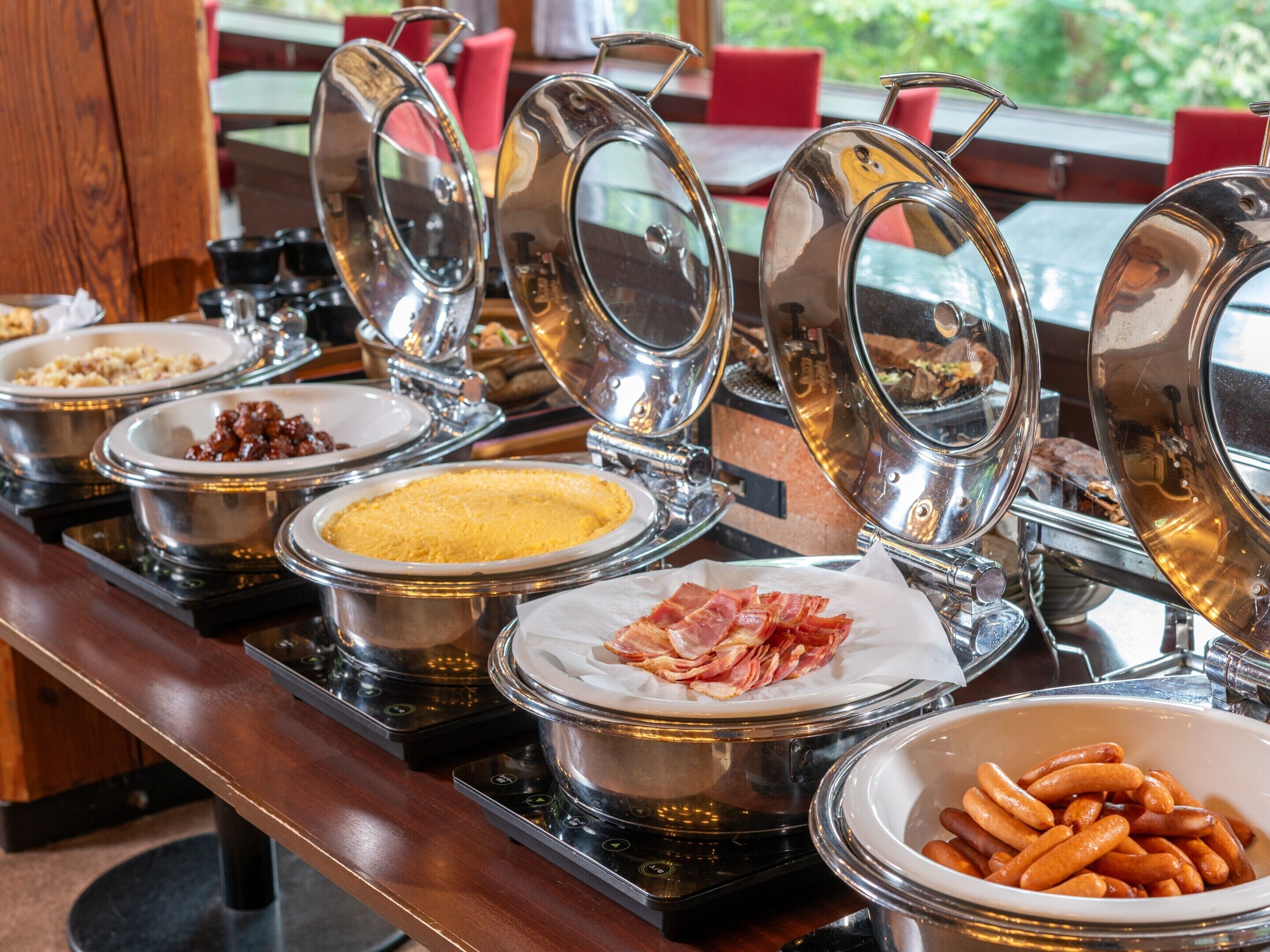 A buffet with various food items in metal containers, including meats and desserts.