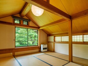 A traditional Japanese room with tatami flooring, a sliding door, a window with a view of greenery, and a ceiling light fixture. - Wan Wan Paradise Takayama (Takayama)