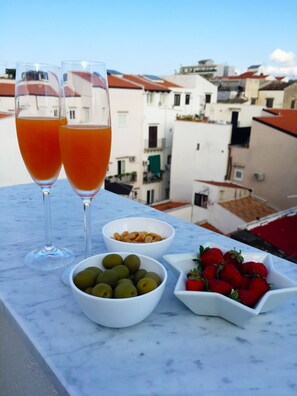 A table with two glasses of orange juice, bowls of olives and strawberries, and a bowl of nuts.