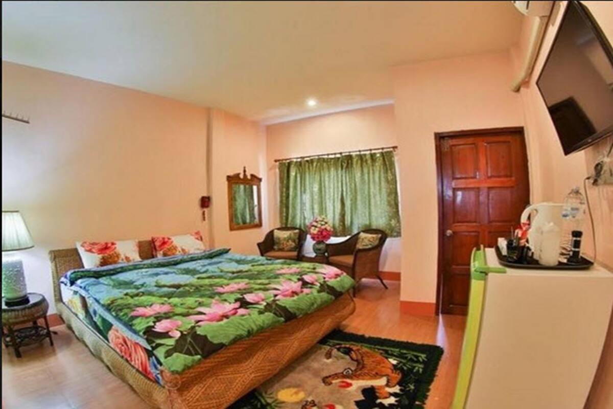 A bedroom with a bed, a desk, a chair, a television, and a door.