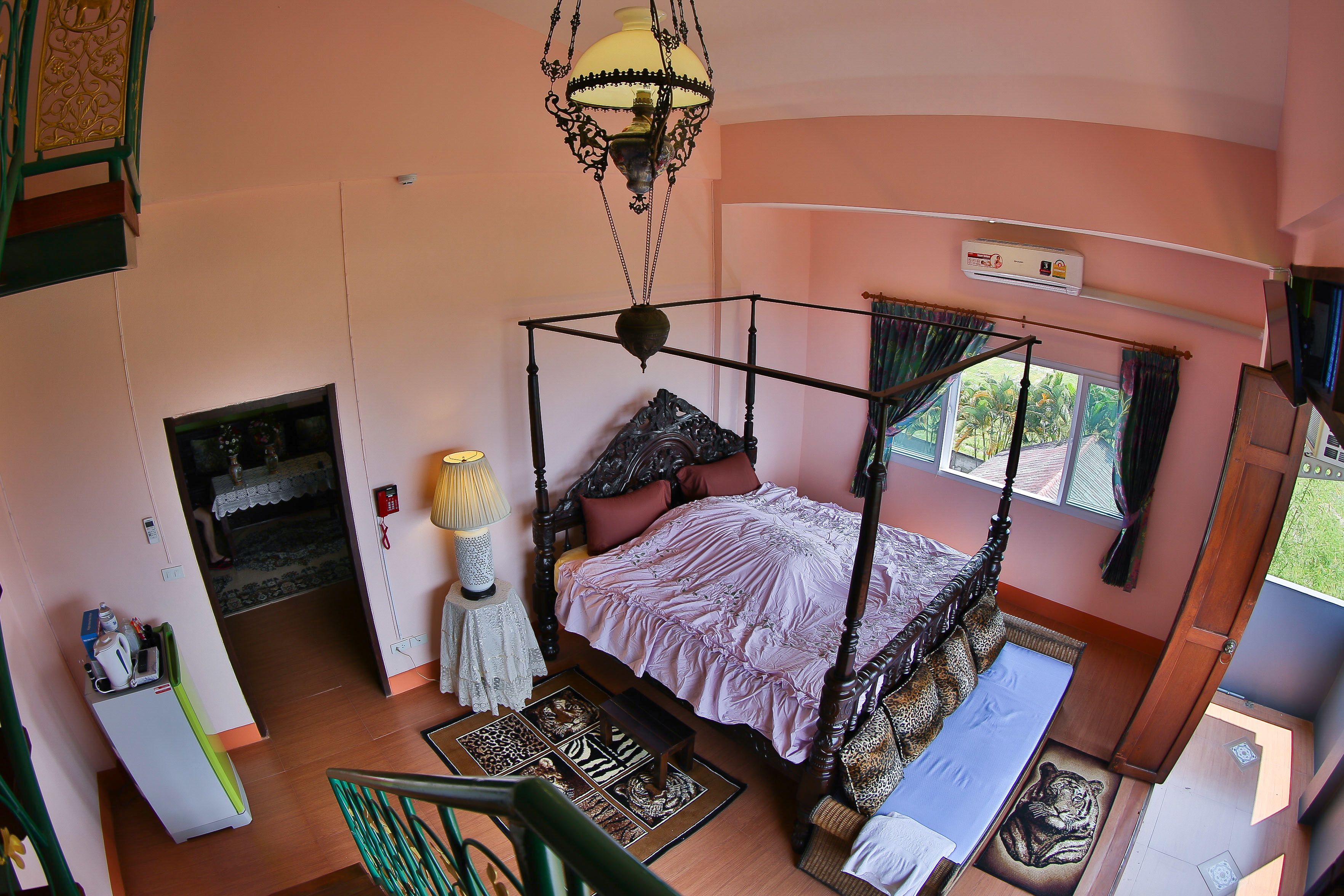 Una cama con dosel y cortina, una mesita con lámpara y vistas al exterior a través de una ventana.