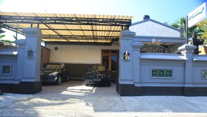 A gated entrance with a covered driveway leading to a building. - Puri Kusuma Guest House (Tabanan)