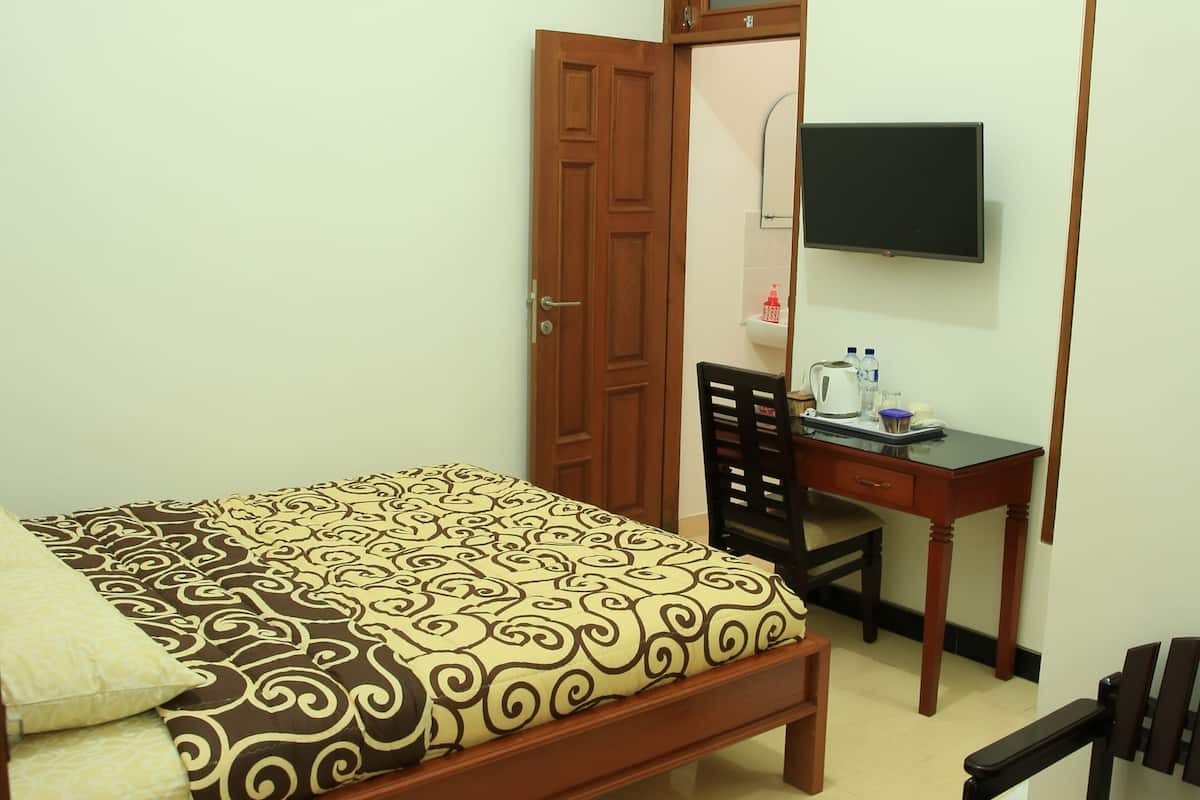 A bedroom with a bed, a desk, a chair, a television, and a wardrobe.