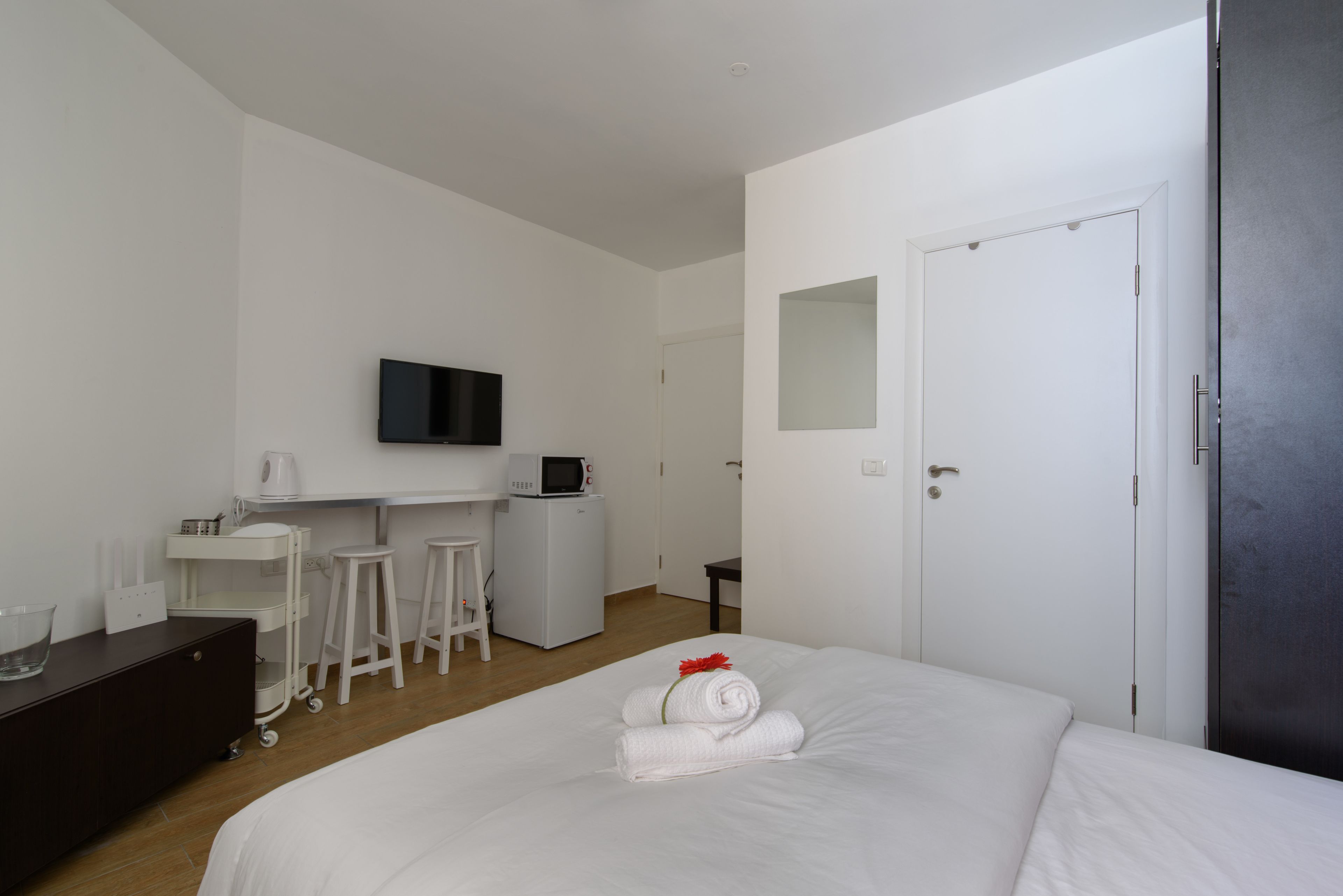 A hotel room with a bed, a desk with a chair, a TV, and a microwave.