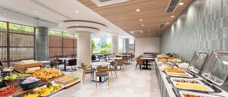 A buffet area with various food options, seating arrangements, and a view of greenery outside.