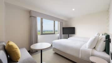 A hotel room with a bed, a sofa, a small table, and a TV.