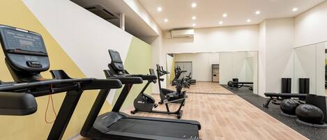 A gym with treadmills, exercise bikes, and free weights.