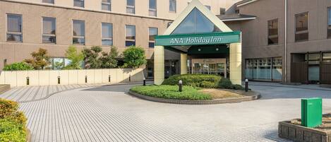 A hotel entrance with a green sign reading 'ANA Holiday Inn.'