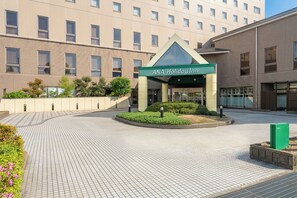 Entrada de hotel con un letrero verde que dice 'ANA Holiday Inn'.