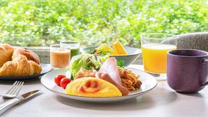 Un desayuno con cruasanes, un plato de comida, un vaso de jugo de naranja y una taza morada sobre una mesa.