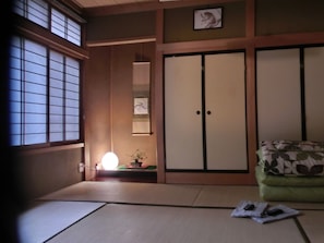 A traditional Japanese room with tatami flooring, sliding doors, and a small table with a lamp.