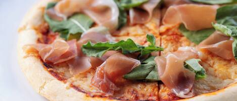 A pizza with prosciutto and spinach on a white plate.