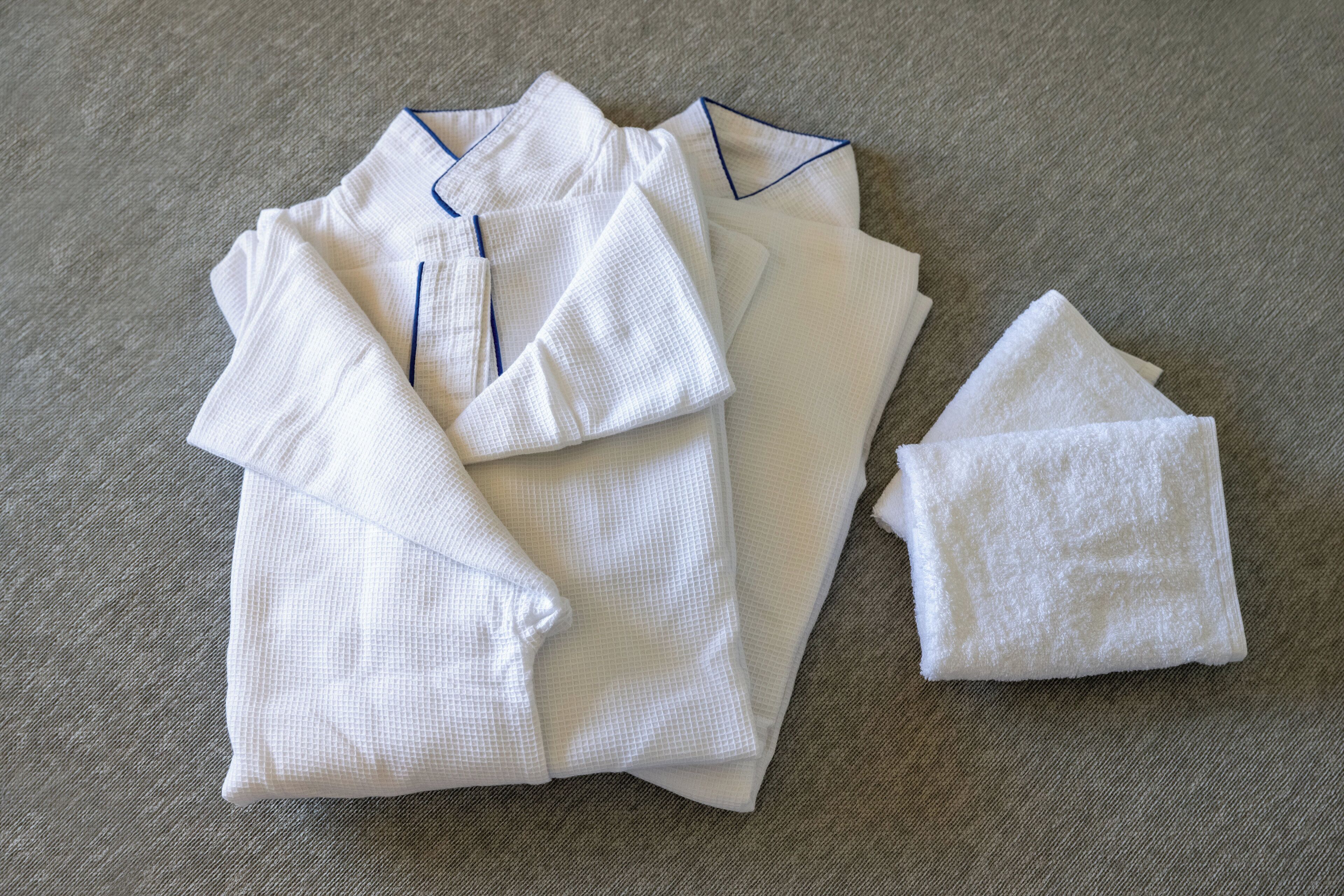 A neatly folded white shirt with blue piping on a textured grey surface.