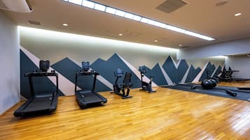 A gym with treadmills, stationary bikes, and a mirrored wall.